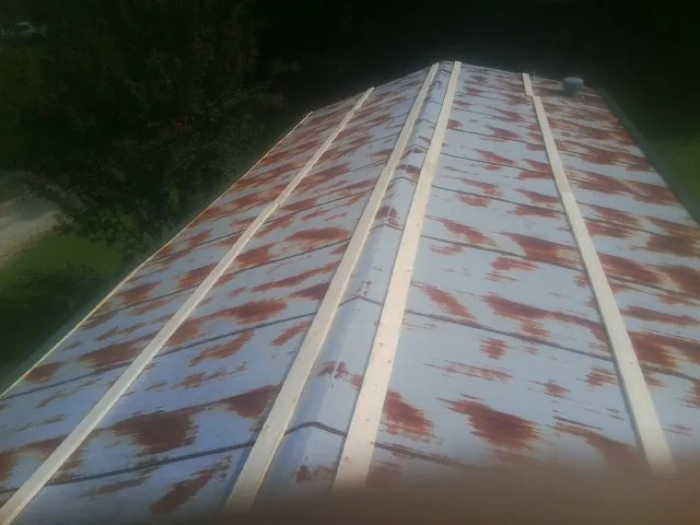 Rusted metal roof panels with new wood purlins before replacement — Storm Damage Roof Repair in Stony Brook by Roofing Brothers