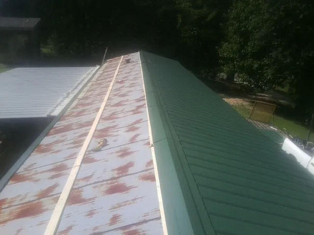 Old rusted panels beside newly installed green metal roofing — Wind Damage Roof Repair by Roofing Brothers in Stony Brook
