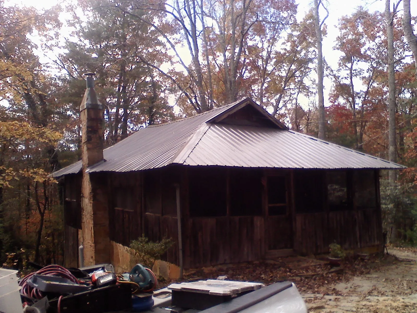 Brown metal hip roof on an old cabin with a stone chimney in Stony Brook