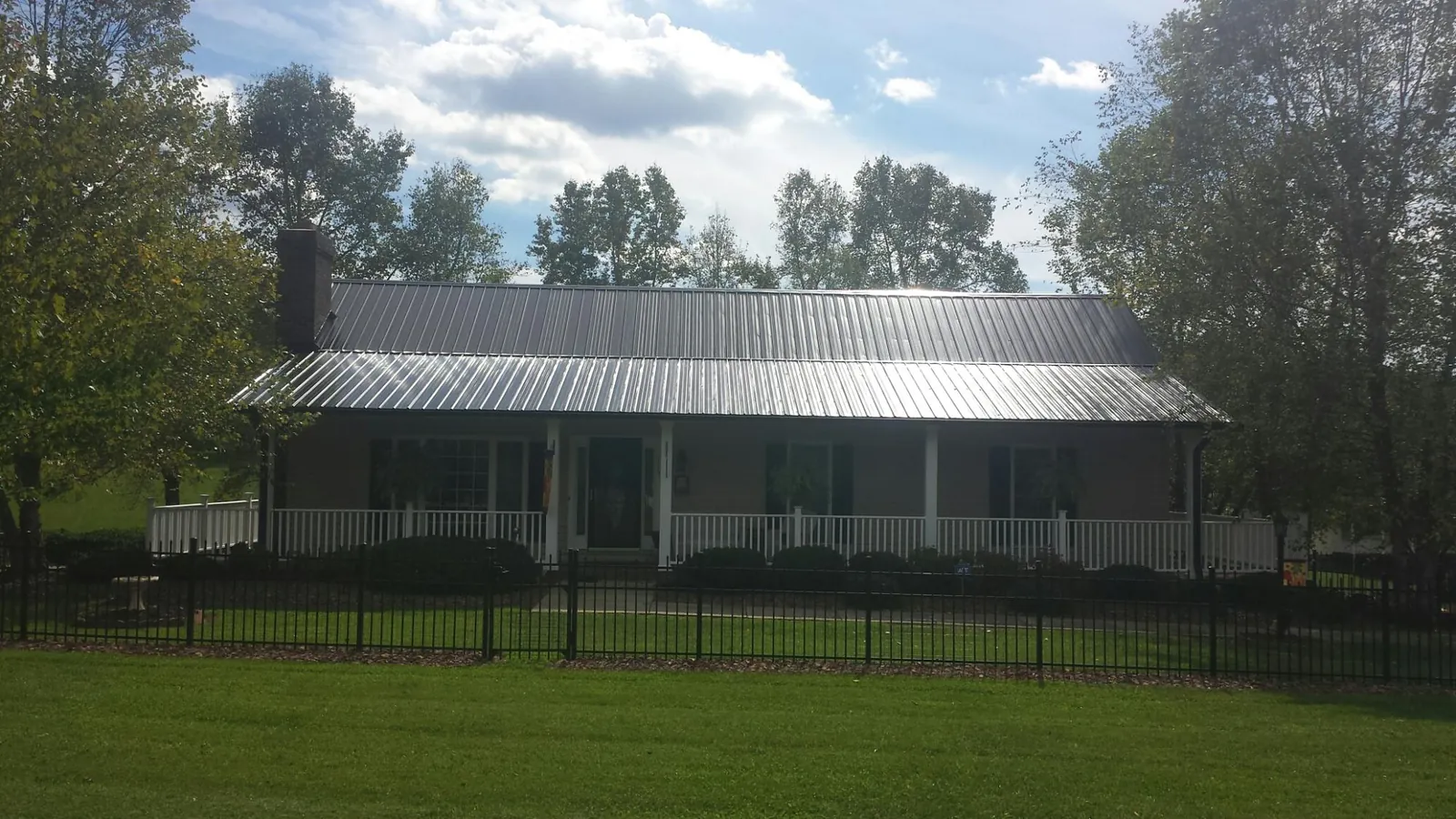 Gray metal roof on a brick ranch with a full width front porch — Gutter Guard Installation work by our crew in Stony Brook