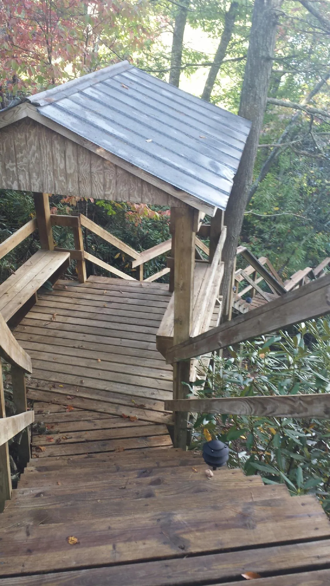 Metal roofed shelter over wooden steps on a wooded walkway — Skylight Repair & Installation work by our crew in Stony Brook