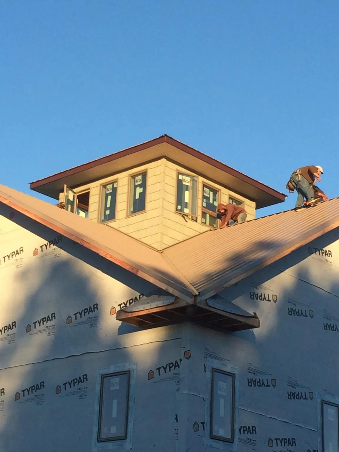 Roofers working around a rooftop cupola on a new metal roof at sunset — Roof Waterproofing in Stony Brook by Roofing Brothers